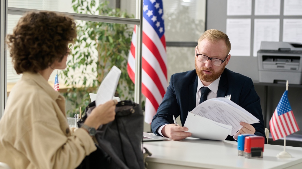 male worker revising documents of young woman applying for green card