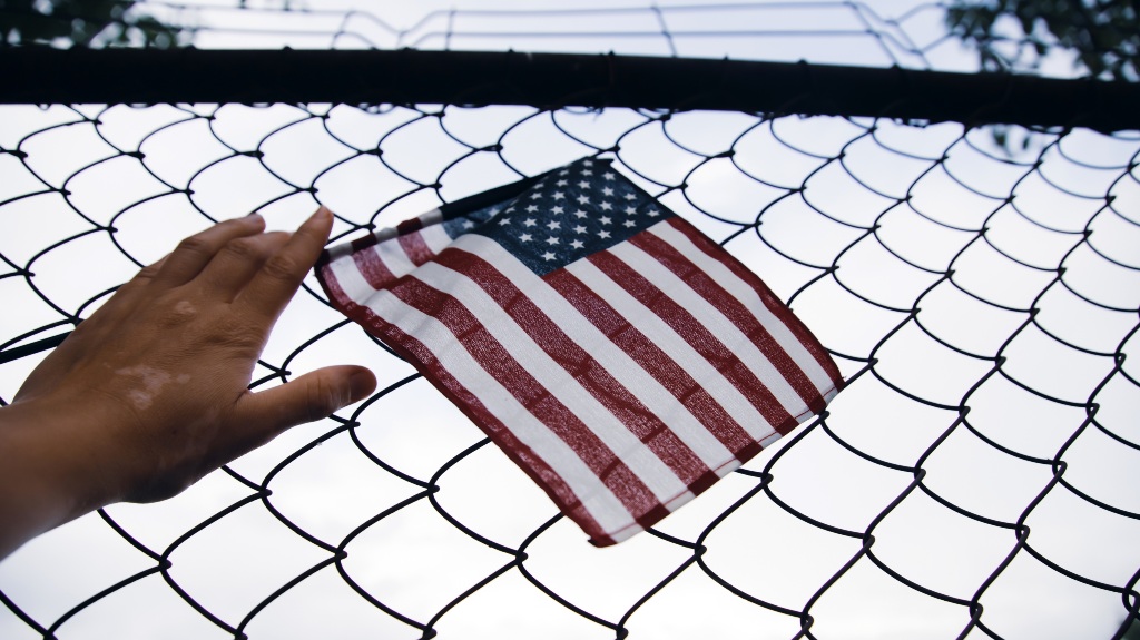 American Flag in hand attached to a chain link fence