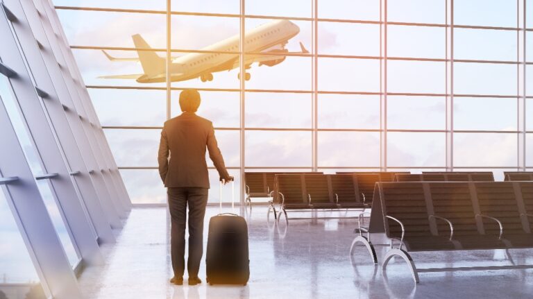 man and a suitcase in airport interior with plane