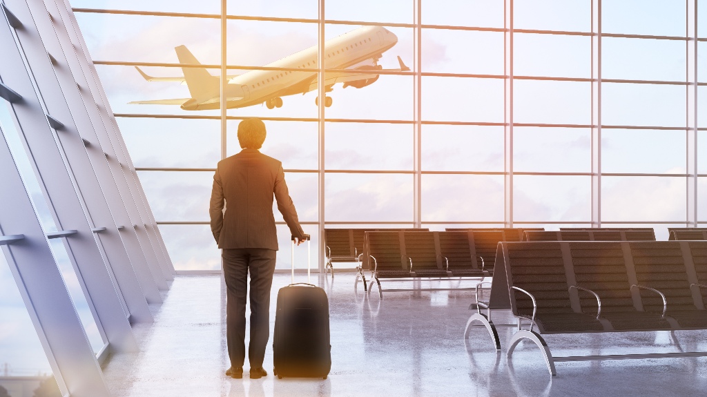 man and a suitcase in airport interior with plane