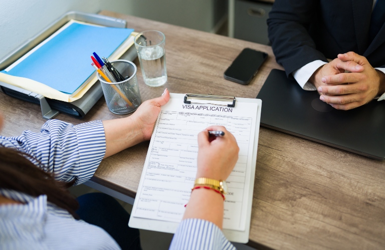Woman completing a visa application form with guidance from a visa consultant